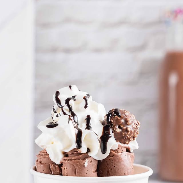 Chocolate ice cream rolls topped with whipped cream, chocolate sauce, and a Ferrero Rocher